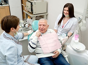 Older dental patient speaking to dental team members