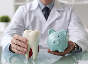 Dentist holding tooth model and piggy bank