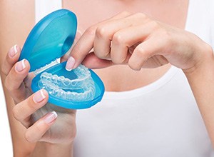 Woman taking Invisalign aligner from its storage case