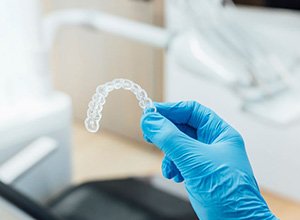 Gloved hand holding Invisalign clear aligner